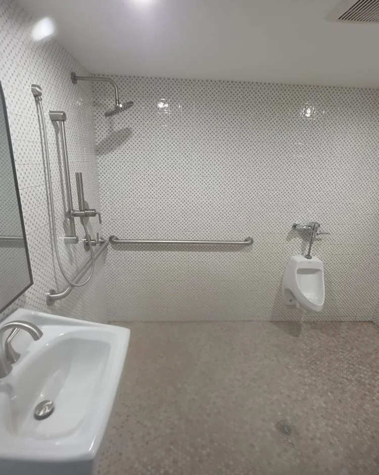 Finished ADA accessible restroom with tiled walls, grab bars and roll-in shower