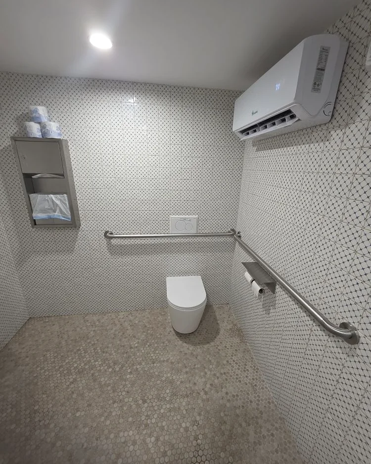 Finished accessible restroom with grab bars, tiled walls and a ductless mini-split