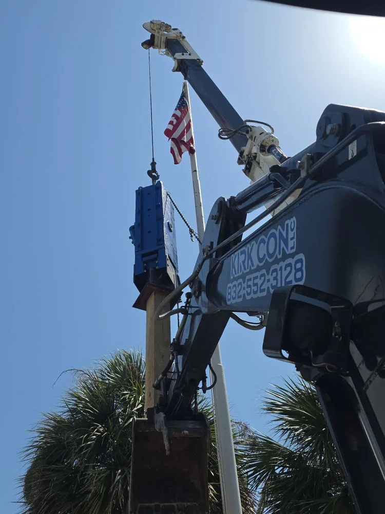 Kirk Con LLC excavator and hydraulic hammer driving a timber piling