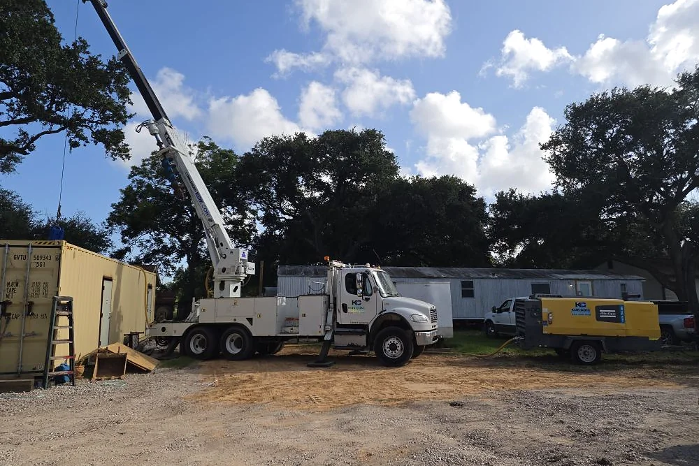 Kirk Con LLC boom truck and equipment staged at a piling installation jobsite