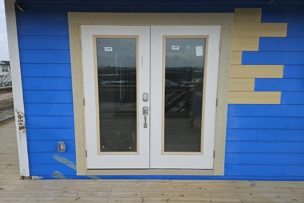 New French doors installed and trimmed into blue lap siding during an exterior remodel